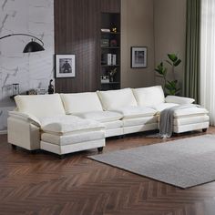 a living room with a white sectional couch and rugs on the wooden flooring