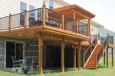 a house with a deck and stairs leading up to the front door, next to a patio