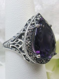 Natural Amethyst Gemstone Teardrop RingTear Vic Design#D28 Inspired by Victorian and Art Deco designs, this high-quality filigree ring is handcrafted in sterling silver. This teardrop ring is set with an 8.37 carat pear cut flawless natural purple amethyst gemstone. The gem is 16mm (~5/8") x 12mm (~1/2"). The gorgeous stones have lovely vibrant color. The inside of the band is marked 925 for sterling silver. Notice the beautiful filigree of the silver setting. This is a ring with beauty and grac Elegant Teardrop Amethyst Ring, Formal Teardrop Amethyst Ring, Elegant Handmade Teardrop Ring, Elegant Teardrop Amethyst Gemstone Ring, Elegant Teardrop Amethyst Ring Gift, Elegant Silver Teardrop Amethyst Ring, Teardrop Amethyst Ring For Gift, Intricate Design Amethyst Ring In Sterling Silver, Intricate Amethyst Ring In Sterling Silver