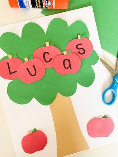 an apple tree cutout with the word lucas on it and scissors next to it