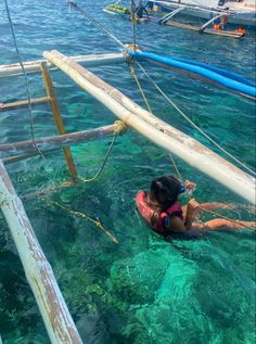 a woman is swimming in the ocean with other boats behind her and holding onto a rope