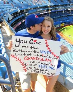 a man and woman holding up a sign in the stands at a baseball game that says you give