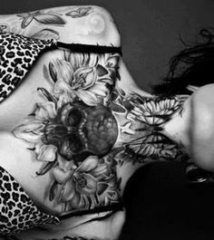 a woman with tattoos on her chest laying down next to a leopard print shirt and skirt