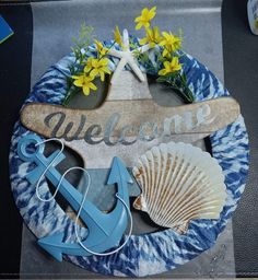 a welcome sign with an anchor, starfish and seashell on a blue plate