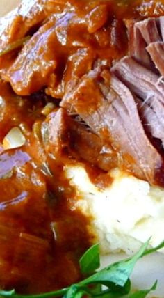 meat and gravy on top of mashed potatoes with garnishes