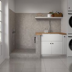 a washer and dryer in a room with tile walls, flooring and white cabinets