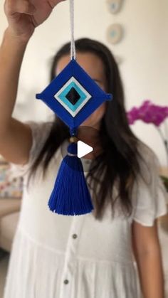 a woman holding up a blue and white ornament in front of her face