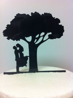 a cake with a silhouette of a man and woman kissing under a tree