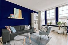 a living room with blue walls and grey couches in it's center area