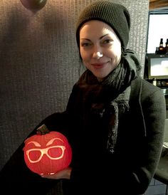 a woman holding a pumpkin with sunglasses on it