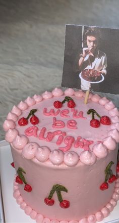 a pink cake with cherries on it and a photo of elvis presley in the background