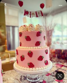 a pink cake with strawberries on it sitting on a table next to other desserts