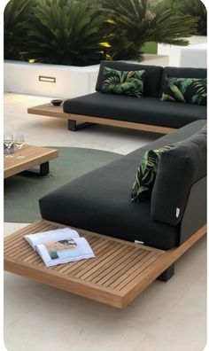 a living room with black couches and green pillows on the table in front of it