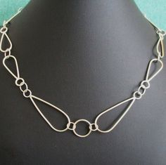 The Art Deco Style argentium sterling silver links of this chain are composed of 2 sizes, the main tear drop shapes are 1.5 inches in length X 1/2-inch wide, center circle is 1/2 inch in diameter, and the remaining links are 1 inch X 3/8 inch.  The hook is handcrafted using argentium sterling silver.  Necklace is adjustable from 18 to 20 inches.  Finish is shiny, more than shown in pictures.   This chain is light to medium in feel and weight, not too delicate or too bulky, feels great to wear. Silver Teardrop Pendant Chain Necklace, Silver Chain Necklace With Hook And Links For Gift, Sterling Silver Teardrop Chain Jewelry, Sterling Silver Teardrop Drop Necklace With Adjustable Chain, Silver Drop Chain Jewelry, Silver Drop Necklace With Chain Detail, Formal Teardrop Chain Necklace, Classic Silver Drop Necklace With Adjustable Chain, Metal Teardrop Necklace With Silver Chain