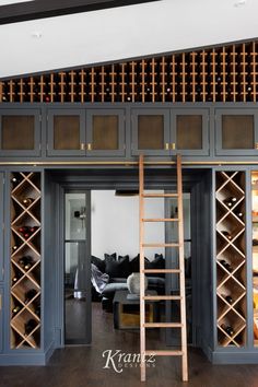 a living room filled with lots of furniture and wooden shelves next to a ladder that leads up to a couch