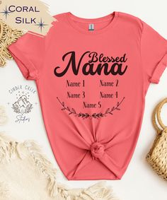 **"Nana Personalized Grandkids" T-Shirt - A Heartwarming Embrace in Every Wear**   Celebrate the special bond between Nana and her grandchildren with our custom "Nana Personalized Grandkids" T-Shirt. This lovingly crafted tee is the perfect way to carry the names of her cherished grandkids wherever she goes. Available in soothing Sand, vibrant Coral Silk, and classic Heather Indigo, and in sizes ranging from S to 3XL, it's the ideal gift for every Nana who holds her family close to her heart. Mother's Day T-shirt With Lettering, Mother's Day T-shirt With Lettering As A Gift, Mother's Day Gift T-shirt With Lettering, Red Tops With Text Print For Mother's Day, Casual Personalized Pink Tops, Casual Personalized Pink Top, Short Sleeve Tops With Lettering For Mother's Day, Personalized Red T-shirt With Short Sleeves, Personalized Red Short Sleeve T-shirt