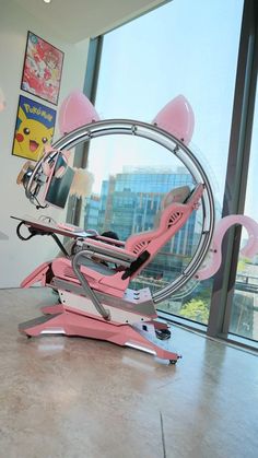 a pink chair sitting on top of a metal stand in front of a large window