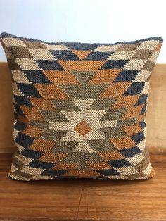 a brown and blue pillow sitting on top of a wooden floor next to a wall