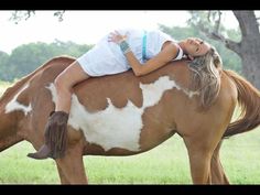 a woman riding on the back of a brown and white horse