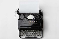 an old fashioned typewriter with paper stuck to it's side and attached to the wall