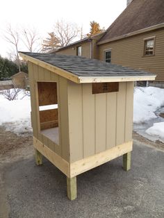 a small wooden outhouse sitting on top of snow covered ground next to a house