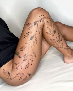 a woman laying on top of a bed next to a white sheet covered in tattoos