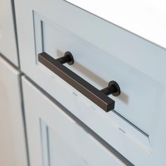 a close up view of the handles on a cabinet with white cabinets in the background