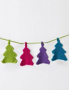 crocheted christmas tree ornaments hanging on a line with green and purple yarns