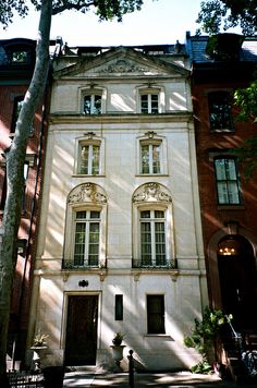 a large white building with many windows on the front and side of it, next to a tree