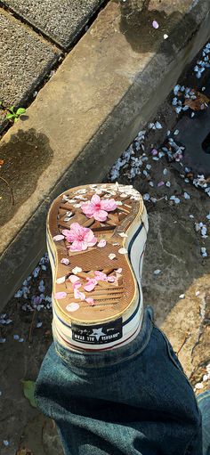 a person's shoe with pink flowers on the ground next to a street curb