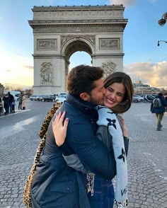 a man and woman hugging in front of the arc de trioe