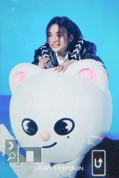 a woman sitting on top of a large white teddy bear pillow in front of a blue background