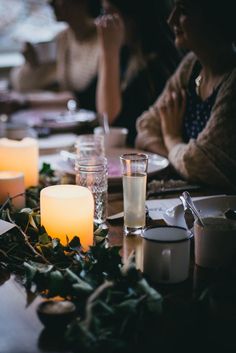 people sitting at a table with candles in front of them