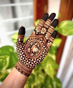 a woman's hand with hennap on it and some plants in the background