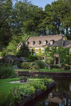 a large house sitting next to a river in the middle of a lush green forest