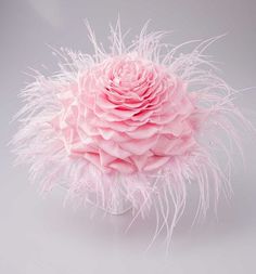 a large pink flower with white feathers on it's head and center piece in the shape of a ball