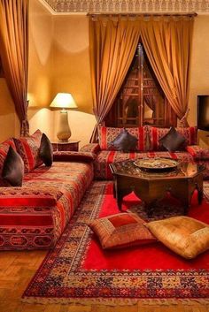 a living room filled with lots of furniture and pillows on top of red rugs