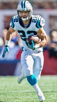 a football player running with the ball in his hand and people watching from the stands