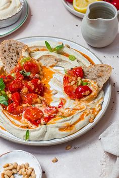 a white plate topped with hummus and tomatoes