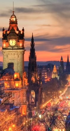 a clock tower in the middle of a city at night with lights all around it