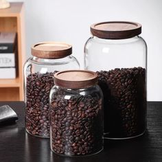 three glass jars filled with coffee beans on a table