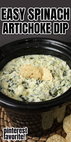 spinach artichoke dip in a black bowl with crackers