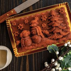 there is a cake that looks like people in the snow on this plate with holly branches