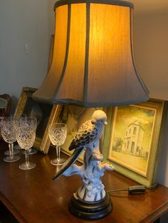 a lamp that is sitting on top of a table next to a painting and wine glasses