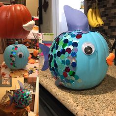 two pumpkins decorated to look like fish with different colors and shapes on them sitting on a counter