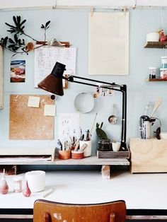 a desk with a lamp and some pictures on the wall above it, along with other office supplies