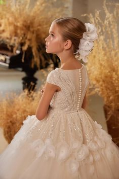 A splendid ballgown in a creamy ivory hue captivates with its charm, as it showcases a shimmering cascade of sequins that gracefully wind from the bodice to the waist, akin to vines elegantly adorning a trellis. The enchanting pattern is further adorned with a delicate garland of flowers encircling the dress, lending an exquisite botanical touch to its already exquisite design. To complete this mesmerizing look, a trail of lustrous pearl buttons graces the spine, infusing the gown with a final f Beaded Flower Girl Dress, Baby Christening Outfit, Flower Girl Gown, Girls Communion Dresses, Fabulous Dress, Flower Girl Crown, Princess Skirt, Peplum Skirt, Custom Gown