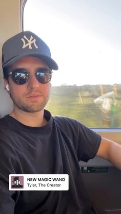 a man wearing sunglasses and a baseball cap is sitting in a vehicle with the window open