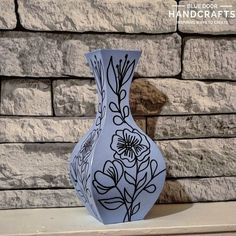 a blue and white vase sitting on top of a table next to a brick wall