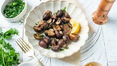 a white plate topped with mushrooms and lemon slices